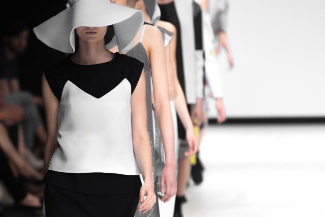 Models wearing striking geometric clothing walk down the catwalk at London Fashion Week