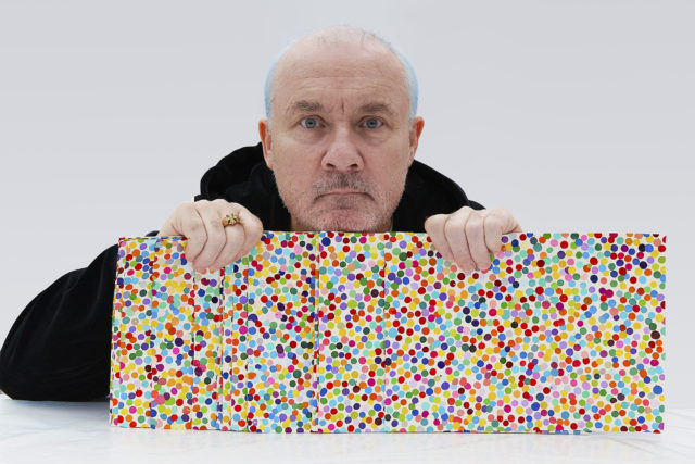 Damien Hirst with The Currency artworks, 2021. Photographed by Prudence Cuming Associates Ltd. © Damien Hirst and Science Ltd. All rights reserved, DACS 2022.