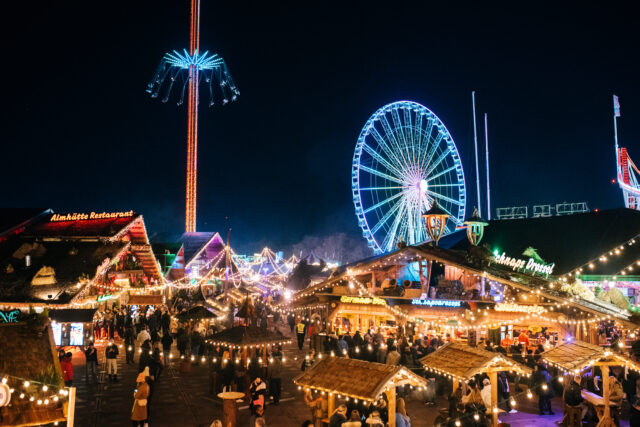 Hyde Park Winter Wonderland is pictured, with wooden chalet market stalls in the foreground and fairground rides including a ferris wheel on the horizon