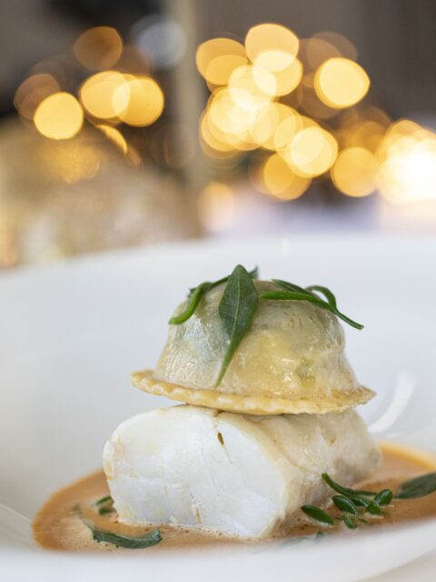 Cornish pollock with crab raviloli is served with a bisque and herbs. Image courtesy of Soho Communications.