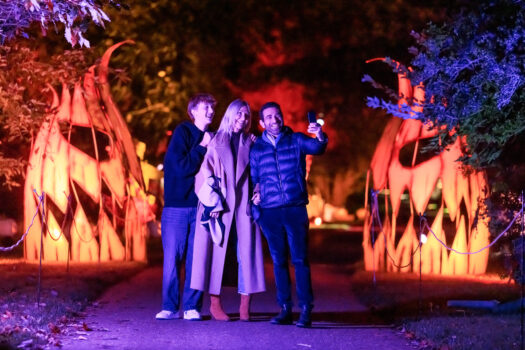 Visitors at Halloween at Kew stand on the footpath between two large pumpkin installations