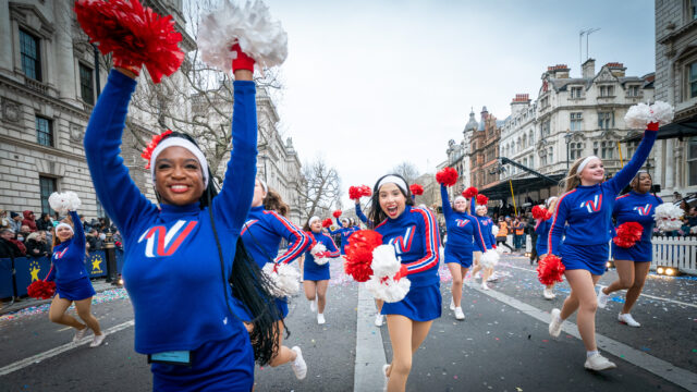 Smiling cheerleaders run towards the camera at London's New Years Day Parade